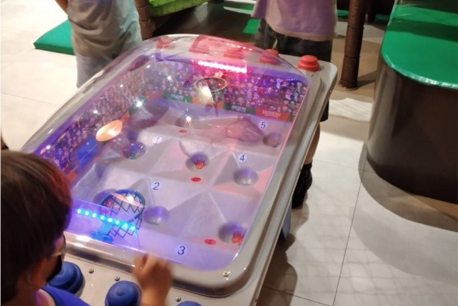 Criança jogando na mesa de air hockey iluminada
