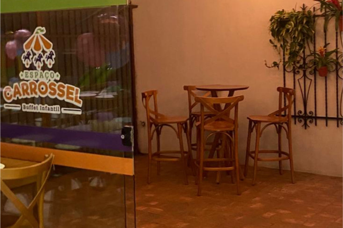 Entrada do Espaço Carrossel com mesas altas e o letreiro do buffet
